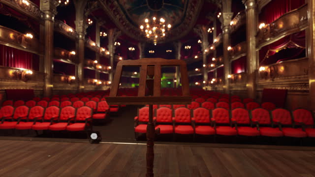 An empty theater with red seats and chandeliers