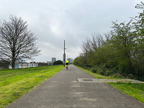 Cyclist on the Greenway, a foot and cycle path that follows the route of an old Victorian sewer in east London. April 2024