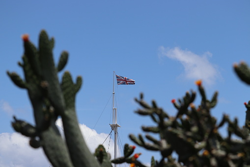 Union Jack flying on a flagpole with a cactus in the foreground on the tropical British Overseas Territory of Ascension Island