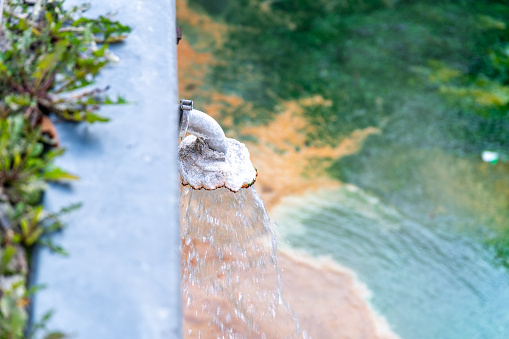 Close-up view of mineral-rich hot spring water flowing into thermal pool in Karlovy Vary