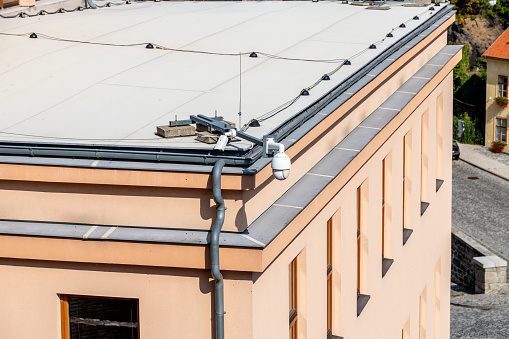 Security cameras on a roof with a sleek peach-colored facade, ensuring safety and oversight