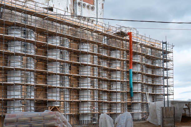 Historic yellow building under renovation with scaffolding and waste chute in Rome