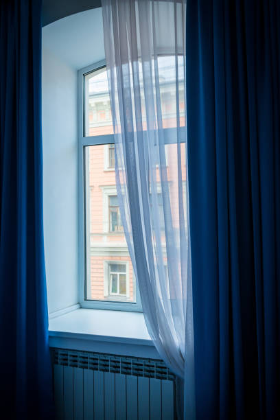 istock A window with blue curtains and a beautifully falling tulle. 2127631970