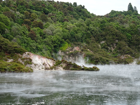 fuming lake in volcanic area of Waimangu, geothermal activity with vapor over water in New zealand