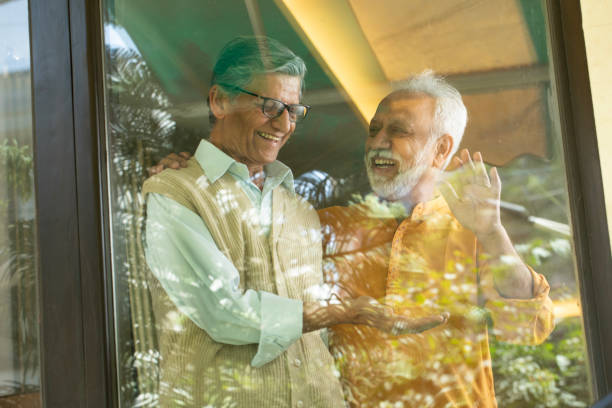 istock Happy senior friends giving high-five seen through window 2127679560