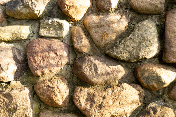 pared de piedra texturizada con luz natural - recubrimiento capa exterior fotografías e imágenes de stock