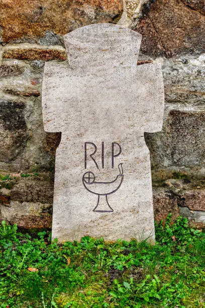 Photo of Weathered Headstone with 'RIP' Inscription and Chalice Drawing