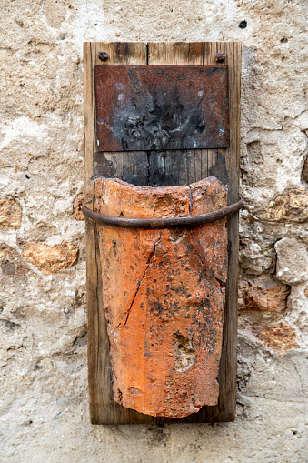 Treviso, Venetien - Italy - 06-08-2021: Rustic terracotta lamp mounted on a weathered wall, blending art and history