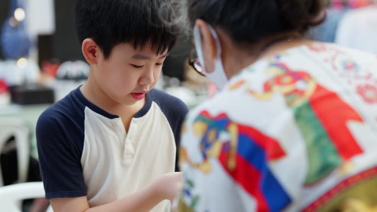 Young boy is enthusiastically selecting a toy car that can transform into a robot at a department store, with the helpful guidance of a salesperson. With a bright smile on his face, the child enjoys the shopping experience, focusing on fun and learning.