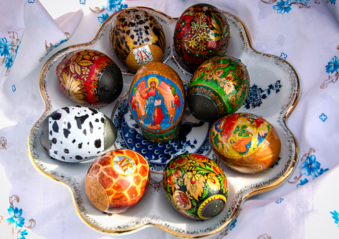 Colourful Easter eggs laid in ceramic plate on white tablecloth. High quality photo
