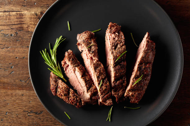 istock Grilled beef steak with rosemary on a black plate. 2127733160