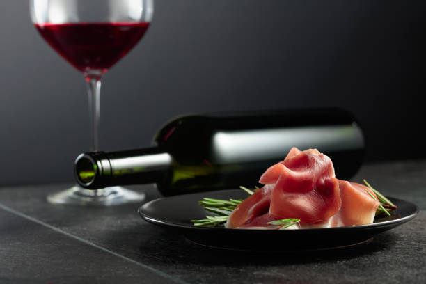 istock Prosciutto with rosemary and red wine on a black background. 2127733685