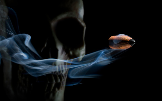 Fatal copper plated bullet with smoke behind coming from a skull