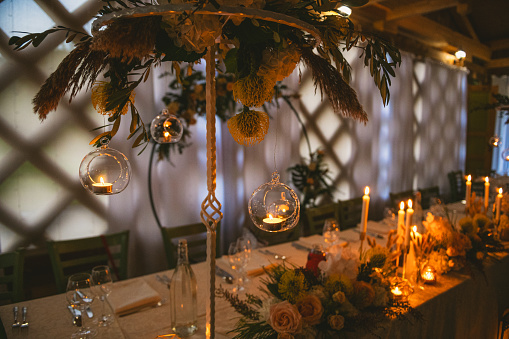 Boho decorated wedding table. Wedding table for a newlywed banquet with eco decor and floral design in the style of boho. Photo taken in low light when candles are lit
