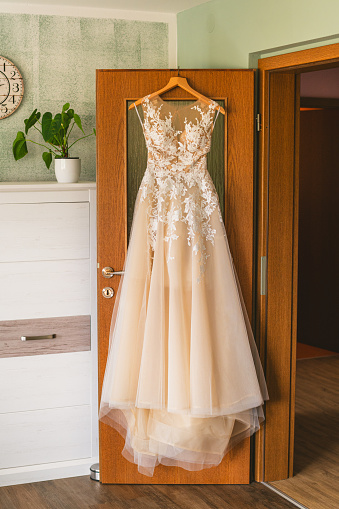 Luxury wedding dress on hanger at the door, getting ready time