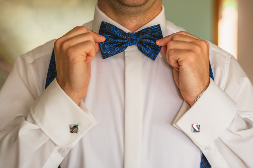Groom holding his blue bow tie