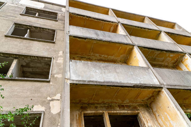 Old prefabricated building left to decay, without windows with balconies that are slowly becoming overgrown