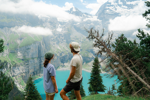 Cheerful man and woman hiking near Oeschinensee lake in Swiss Alps