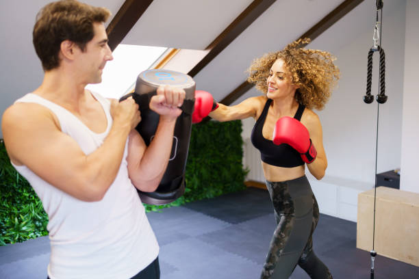 Strong sportswoman punching bag during workout with personal coach