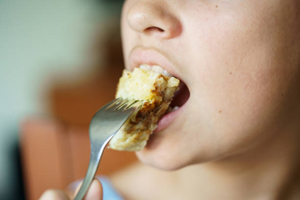Crop anonymous girl eating fresh yummy Spanish potato omelette from fork