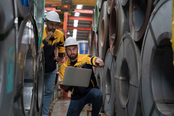 istock Two male engineers workers using laptop computer inspecting quality rolls of galvanized or metal sheet in in aluminum material warehouse. Group of male workers working in warehouse 2127944522