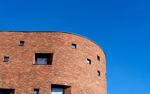 Old City high rise with red bricks on blue sky background,Minimal red brick wall on clear summer sky,Traditional antique exterior detail of residential apartment building with brick facade in England