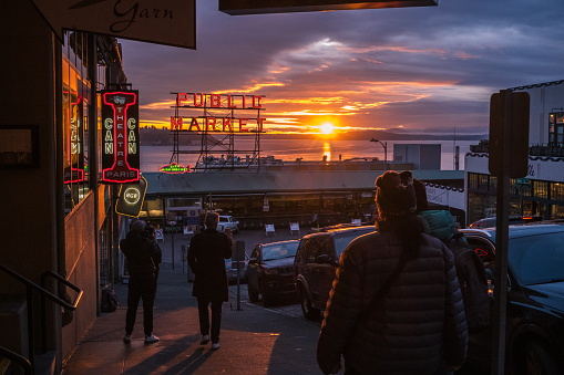Seattle, USA – Feb 19, 2024: Late in the day tourists at the iconic Pike Place Market sign during a vivid sunset