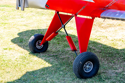 Caorle, Venetien - Italy - 06-14-2021: Vintage red biplane on a lush Italian meadow, showcasing front wheels and wings