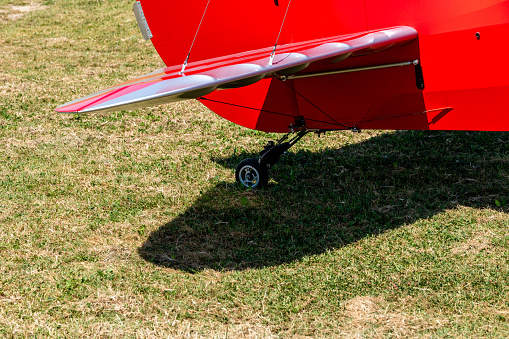 Caorle, Venetien - Italy - 06-14-2021: A detailed view of the tail wing and landing gear of a red airplane in a meadow
