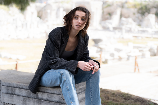 Fashion portrait of young tourist woman in a historical archeological ancient town ruins.