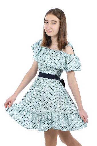 Young beautiful girl in a dress with polka dots on a white background. High resolution photo. Full depth of field.