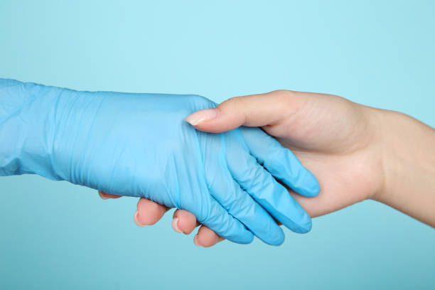 istock Doctor and patient shaking hands on blue background 2128012432