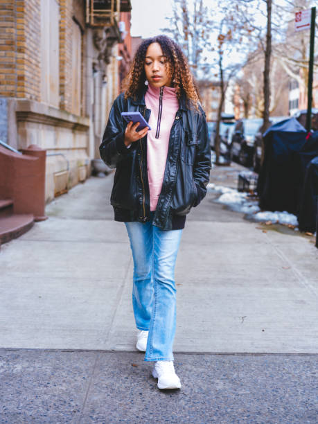 istock Social media on smartphone and  strolling NYC suburbs' sidewalks. 2128023379