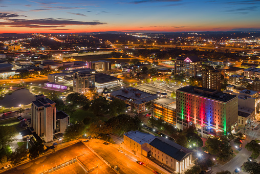 Aerial of Downtown Huntsville at dusk / sunset, with a highly illuminated cityscape and Big Spring Park on the left.