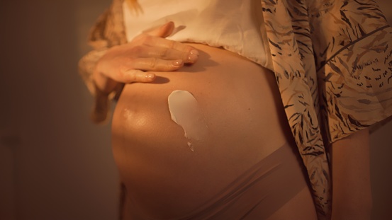 White mehendi on big pregnant belly. Expectation of baby in boho lifestyle.