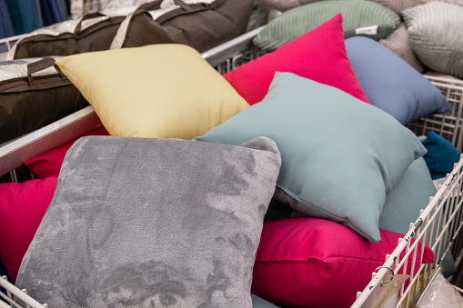Various textile pillows in vibrant colors like electric blue and carmine are piled high in a shopping cart. The rectangleshaped pillows offer comfort and add a pop of color to any room