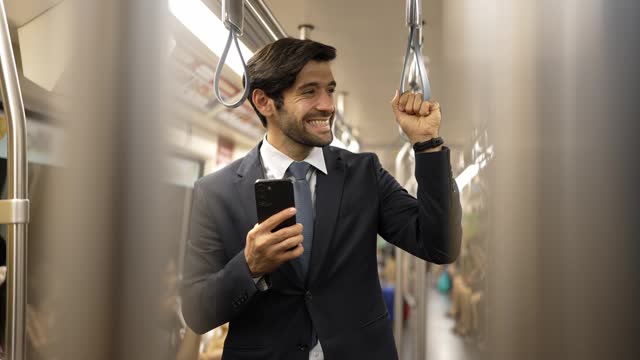 Skilled business man standing in train or subway while holding phone. Exultant.