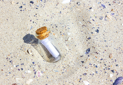 A message in a Corked Bottle on a beach. The bottle in the sand. The bottle on sandy beach. Sunny day.