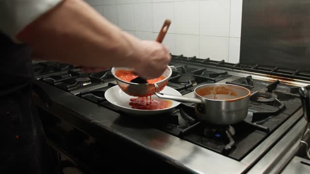 FIltering The Tomato Sauce Inside A Strainer