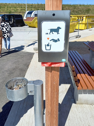Container with dog waste bags with stickers and street ashtray on a city street