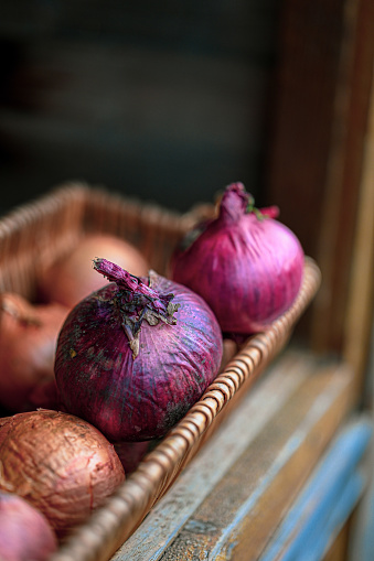 Red and brown onions in a basket on a vegetable stall.