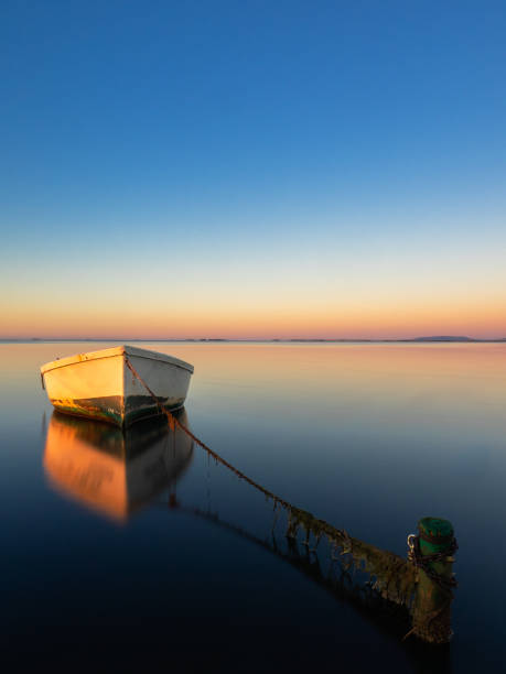 istock Boat anchored on the beach at sunset. 2128173761
