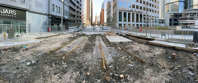 Modern skyscrapers surround the remains of the early electric trolley tracks lined with granite cobblestones recently excavated during construction on Tremont Street adjacent to 16th street mall in downtown Denver Colorado. Trinity Methodist church and the Brown Palace stand in the background. The Denver Tramway Company converted it’s cable car route in 1889 to electric trolley on Tremont. Later in 1905, parts of the line were upgraded and cement was poured in and around the rails and into the cable trenches near the Brown Palace.