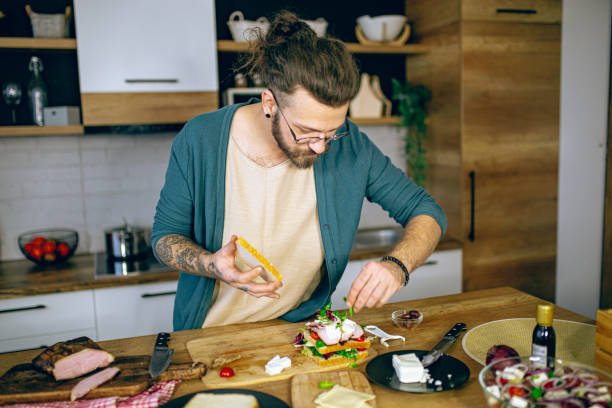 istock Man prepares a club sandwich in the kitchen 2128190442