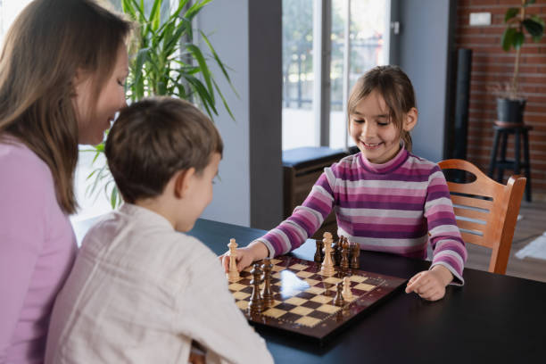 istock Mother and children playing chess at home 2128196863