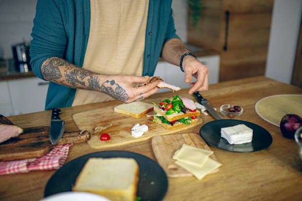 istock Man prepares a club sandwich in the kitchen 2128202568