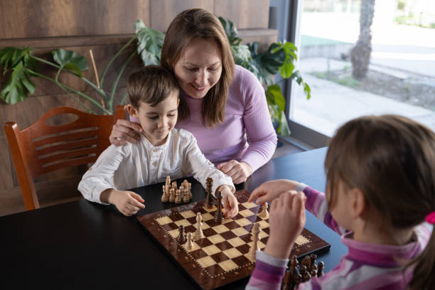 istock Mother and children playing chess at home 2128202572