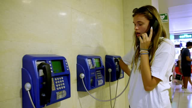 Young Caucasian woman using an pay phone at the shopping mall