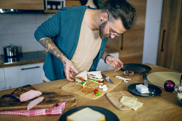 istock Man prepares a club sandwich in the kitchen 2128213608