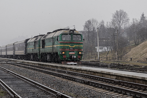 Yasinya, Ukraine. March 17, 2024. cloudy rainy sky. an incredibly beautiful view of the fog-shrouded mountains. a train with people arrived at the platform.